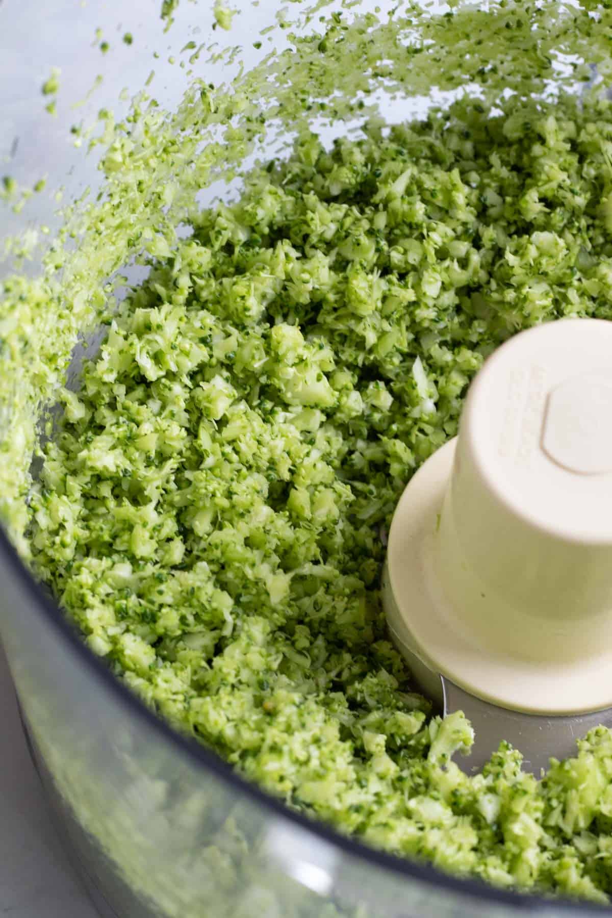close up photo of riced broccoli inside food processor.