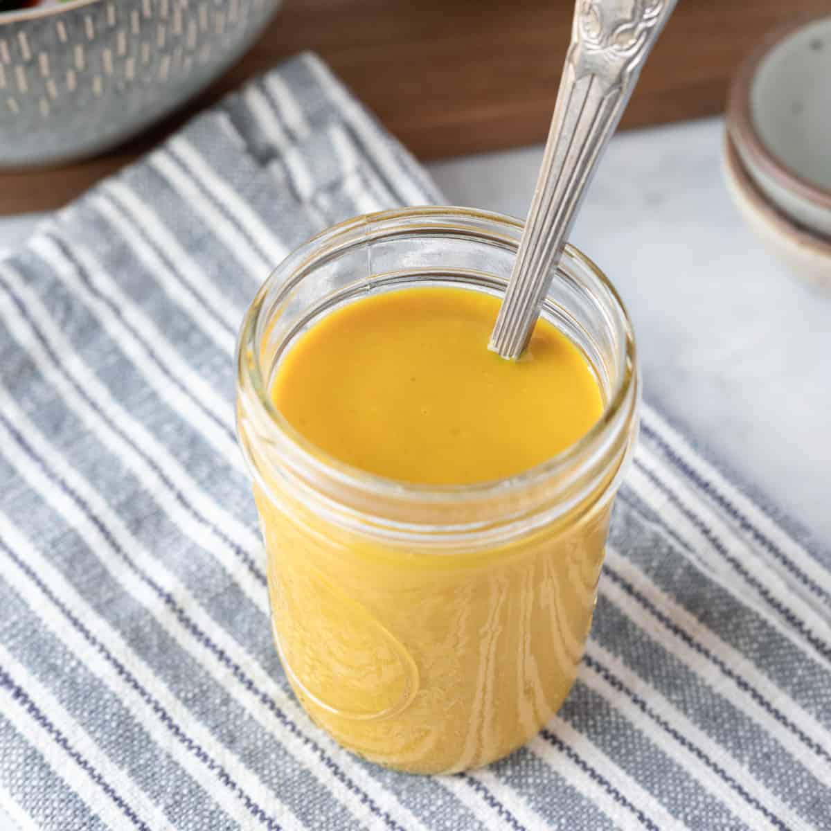close up of bright yellow honey mustard dressing in a jar.