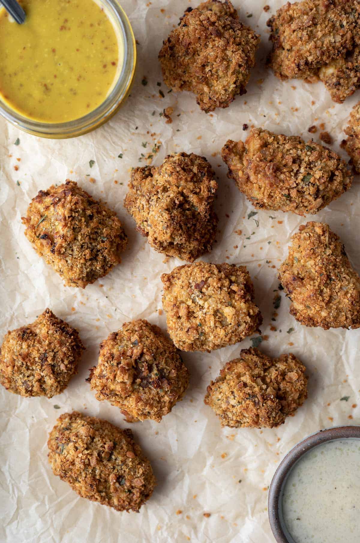 overhead photo of seitan chicken nuggets on a baking sheet with dipping sauces.