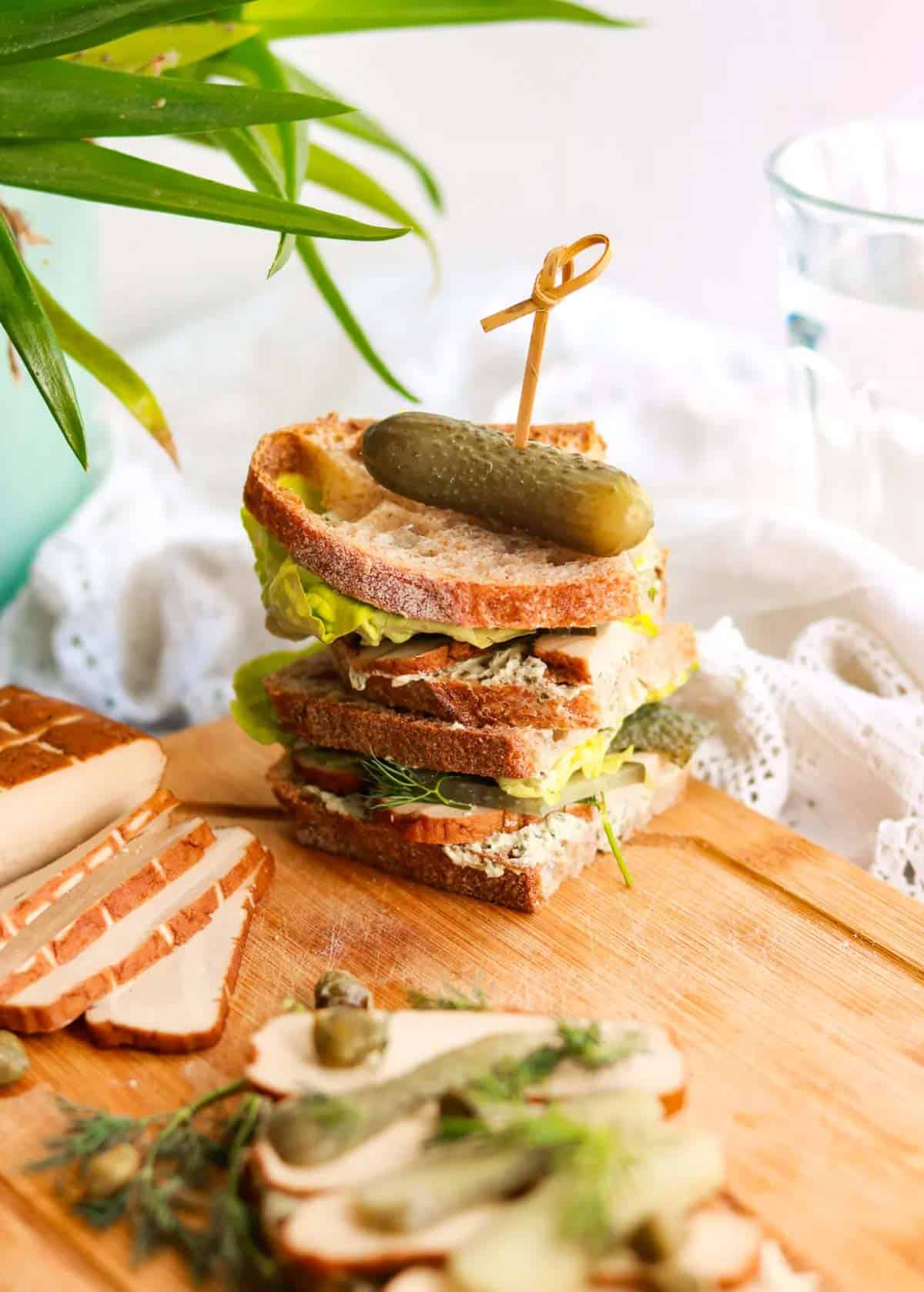 stack of vegan tofu sandwiches on a wood cutting board.