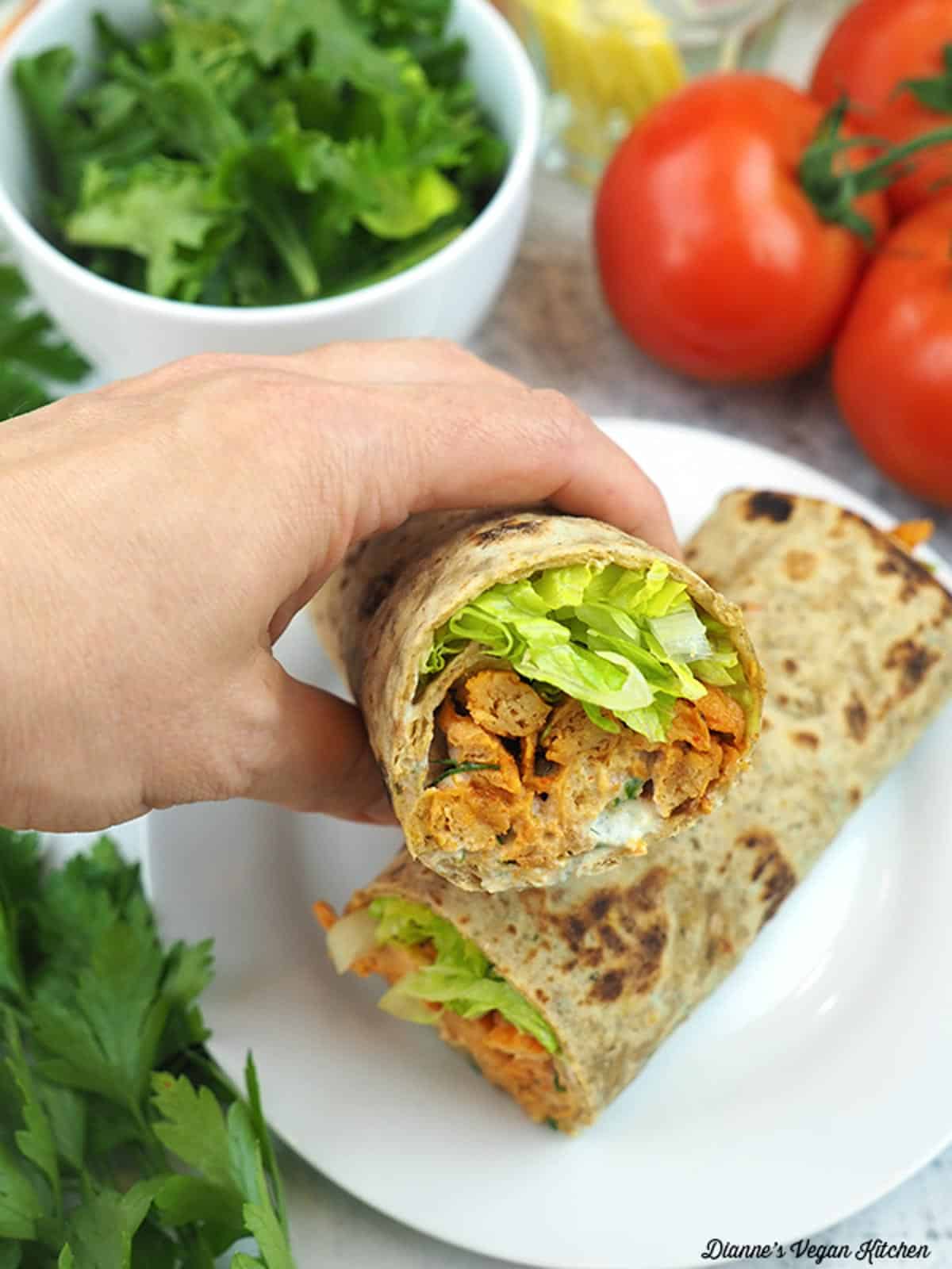 a hand holding up a wrap to show the filling inside.