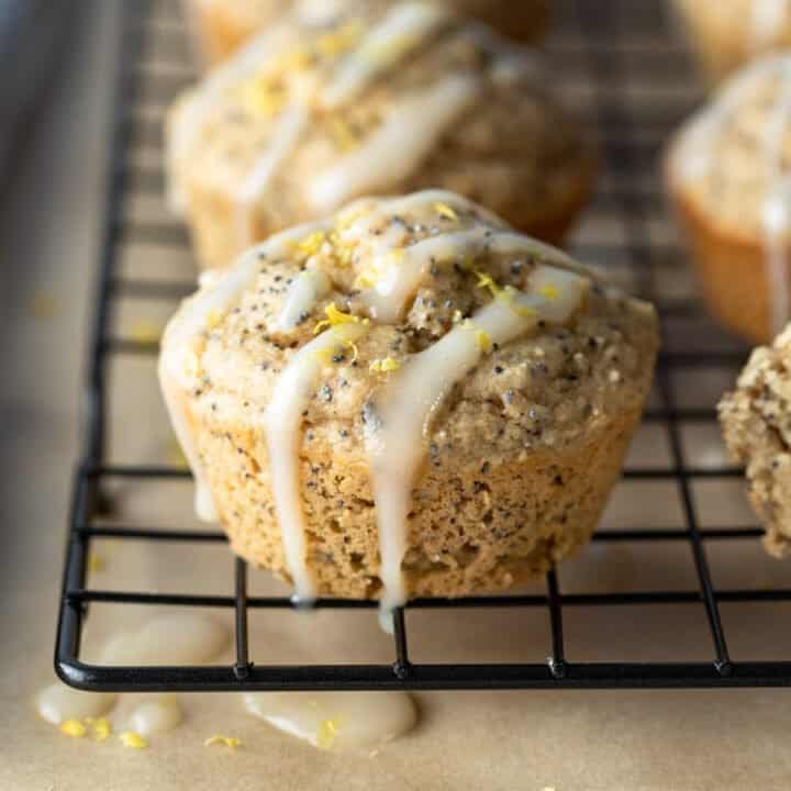 close up of muffins lined up on a cooling rack with icing on top.