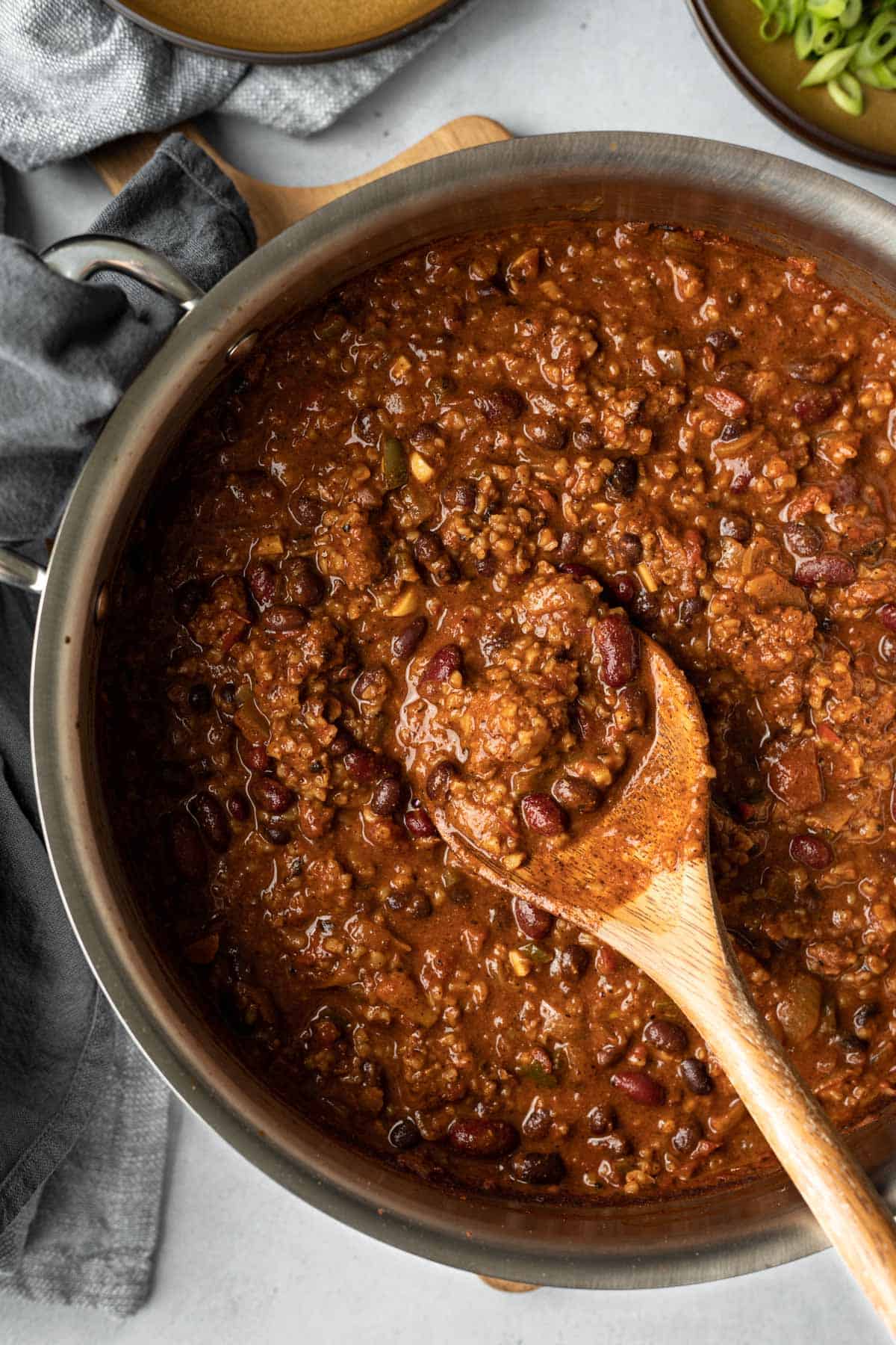 wooden spoon scooping up Beyond Meat chili from a large pot.
