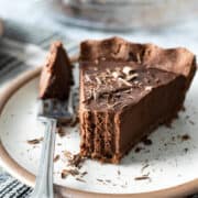 a slice of vegan chocolate pie on a dessert plate with a bite taken out.