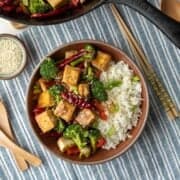 tofu and vegetable stir fry with rice and Szechuan sauce in a bowl.