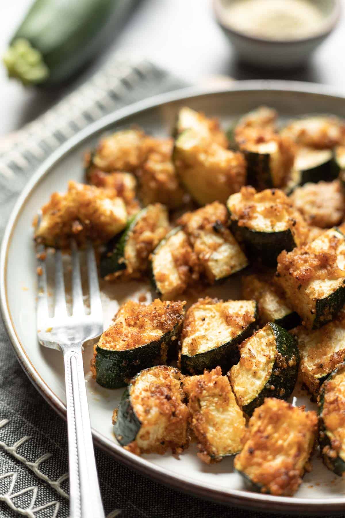 panko breaded bite-size pieces of air fryer zucchini on a plate.