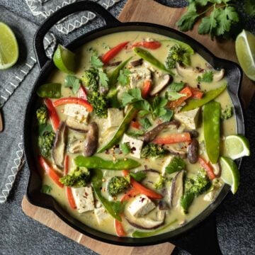 creamy coconut green curry tofu with colorful vegetables in a skillet.