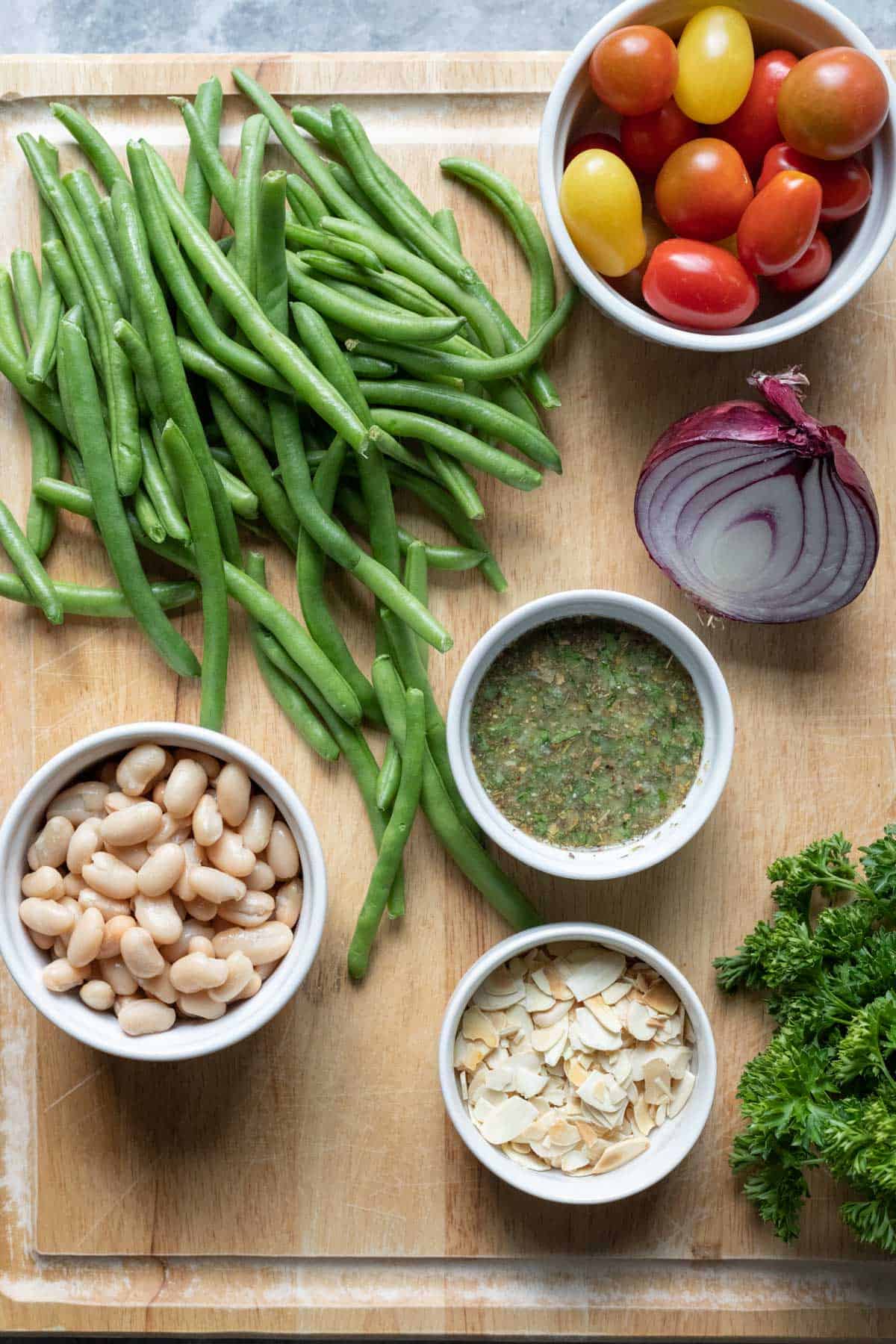 ingredients needed for green bean salad on a large cutting board.