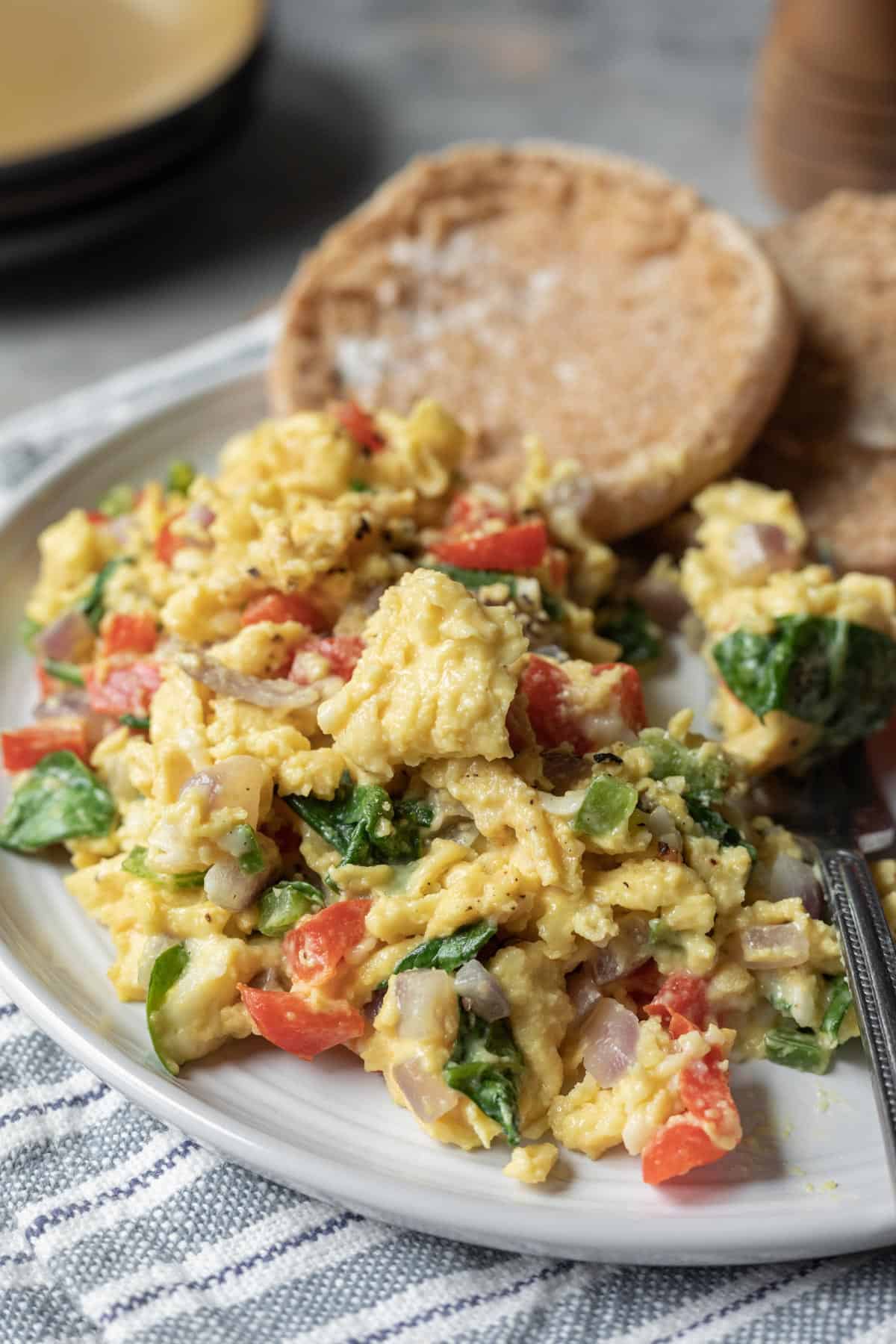 Veggie Just Egg scramble on a plate with an English muffin.