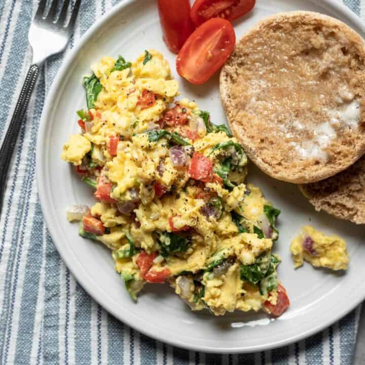 serving of Just Egg scramble with vegetables and English muffin on a plate.
