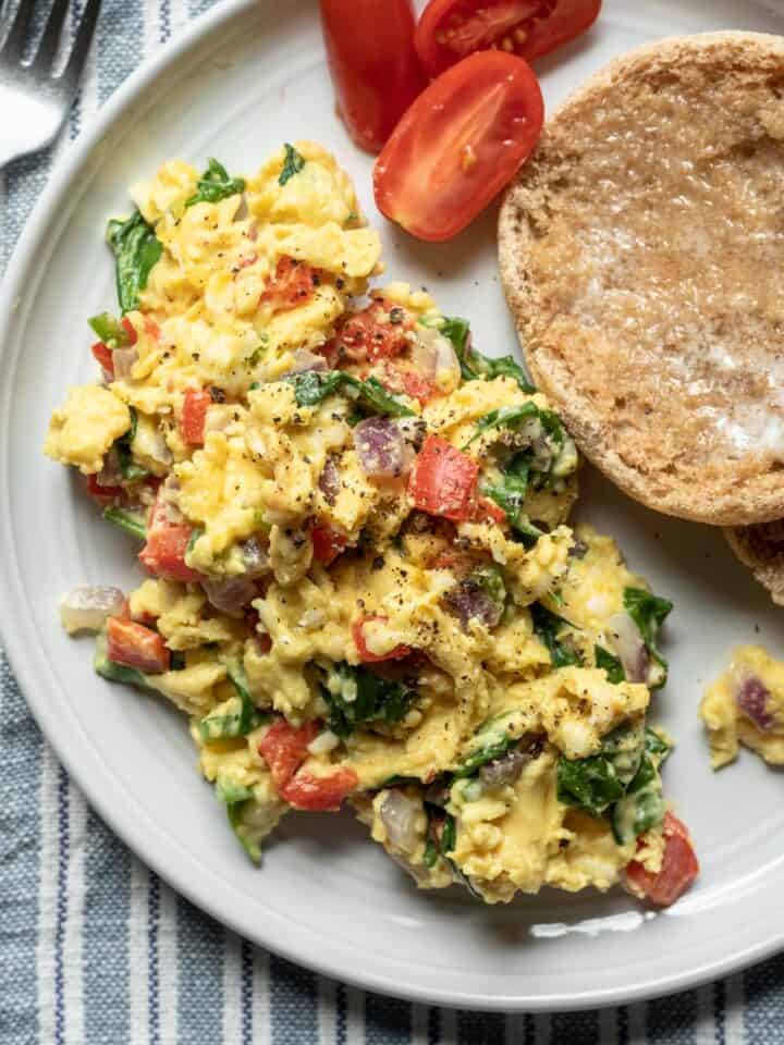 serving of Just Egg scramble with vegetables and English muffin on a plate.