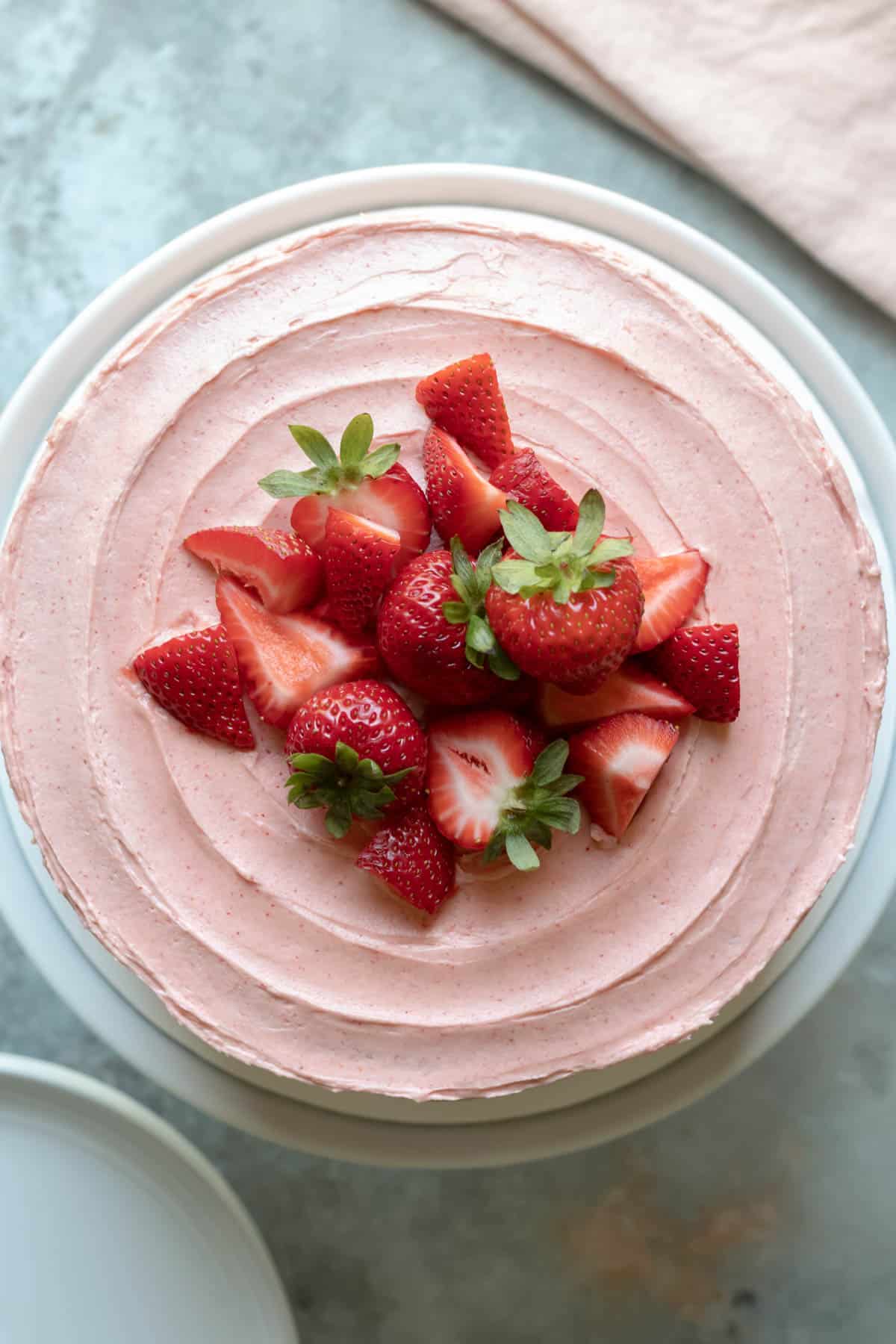 looking down at the top of a layer cake decorated with pink strawberry frosting.