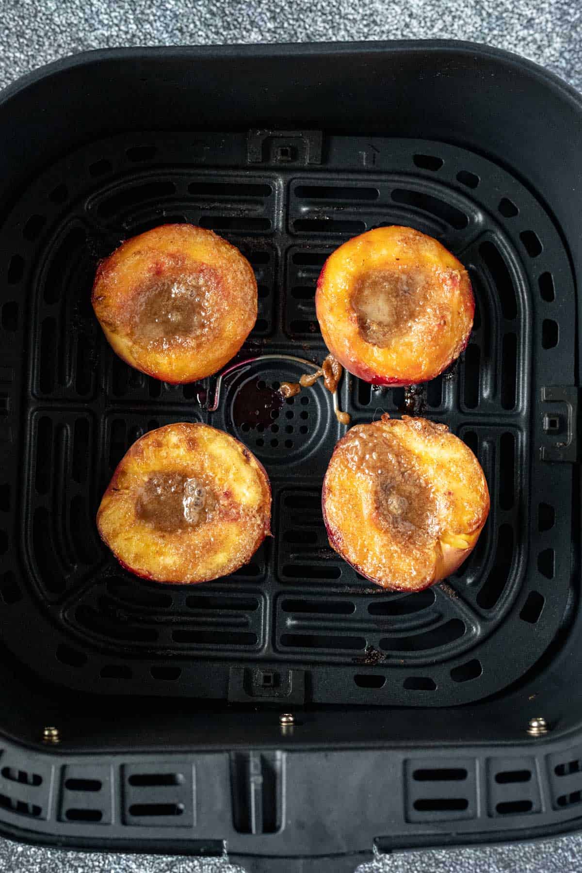 four peach halves after cooking in the air fryer.