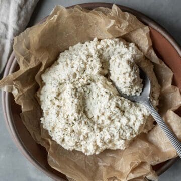 Batch of creamy vegan ricotta in a bowl with a spoon resting on the side.