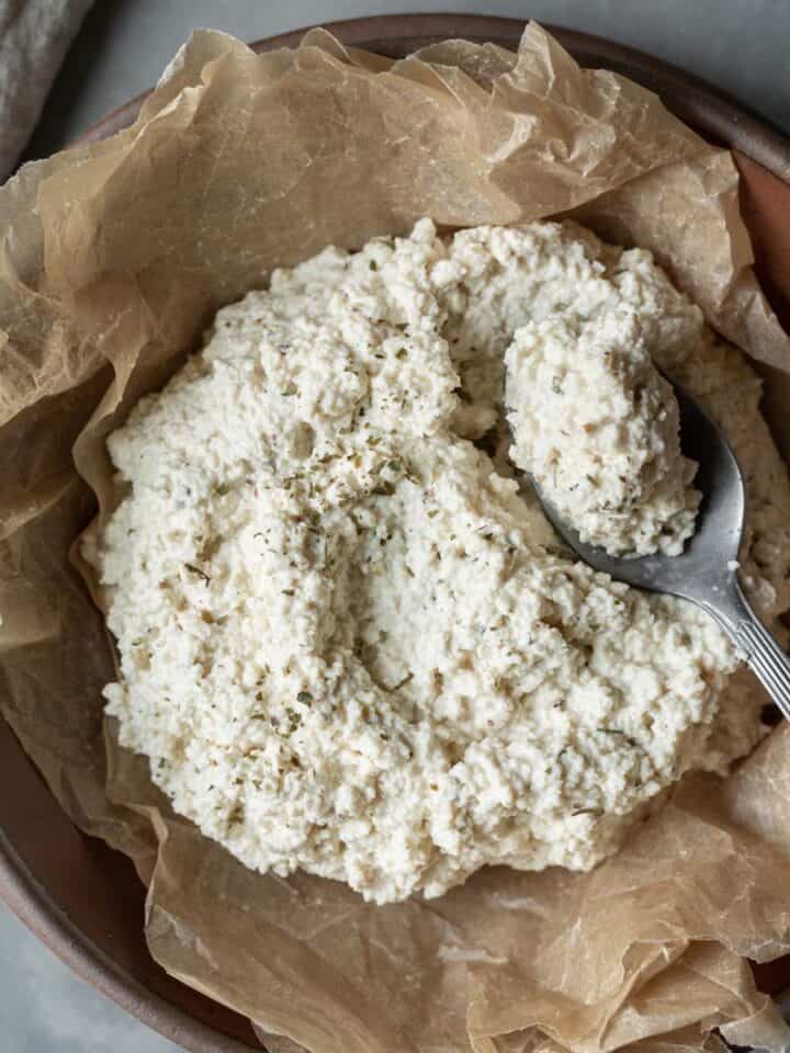 Batch of creamy vegan ricotta in a bowl with a spoon resting on the side.