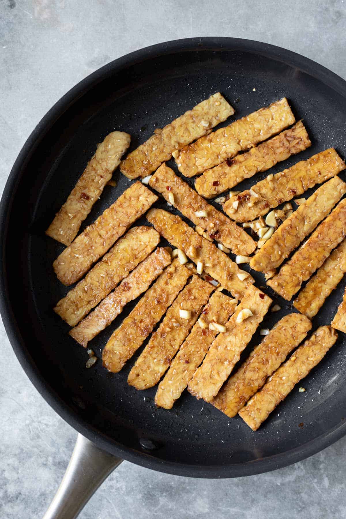 cooking sliced, marinated tempeh in a non-stick pan.