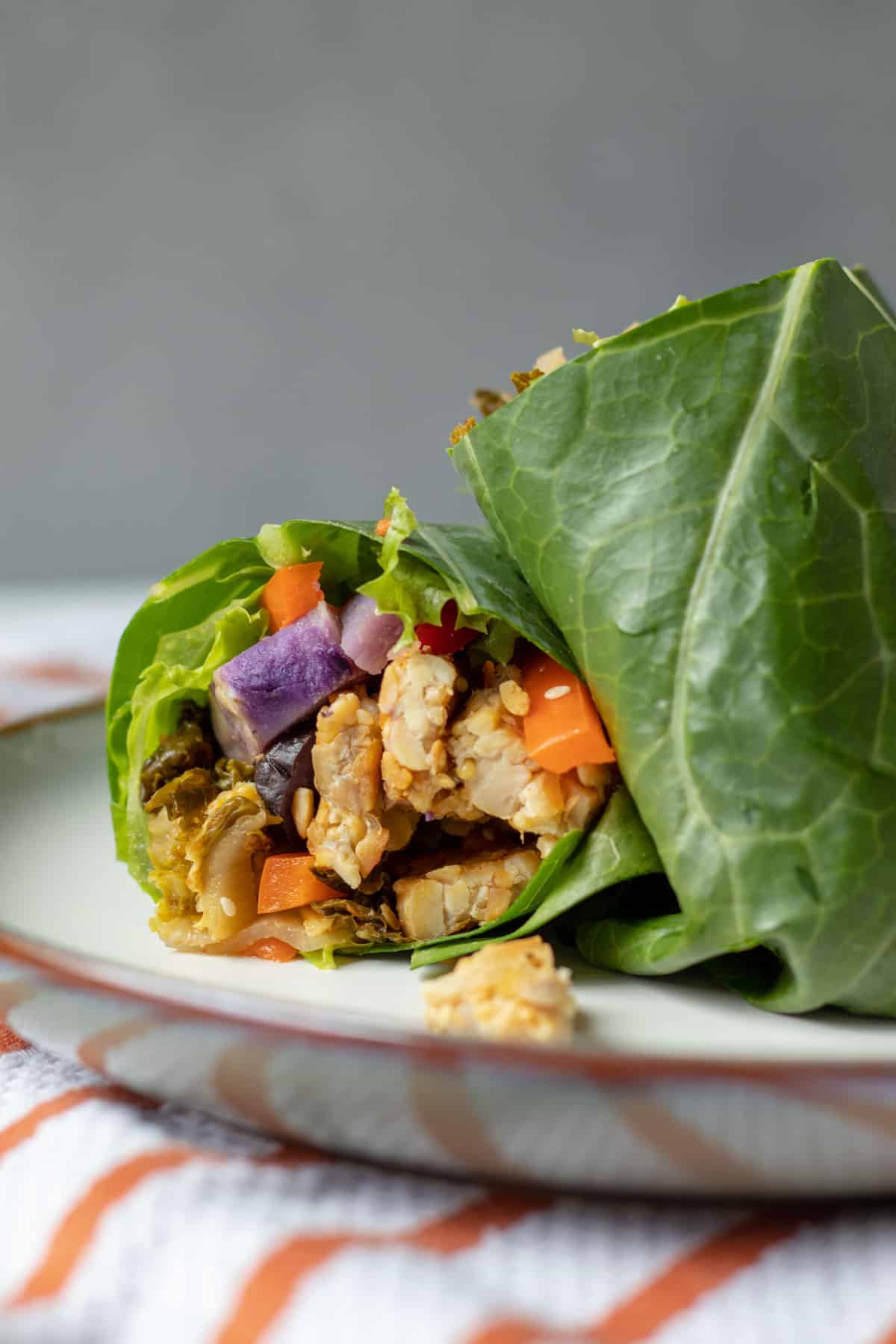 close up of a cut collard wrap showing tempeh and vegetables inside.