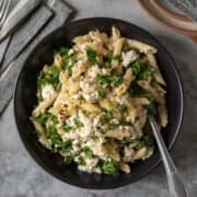 Black bowl filled with vegan pasta made with kale, lemon, and dairy free ricotta.