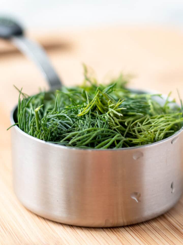 measuring cup full of fresh dill.