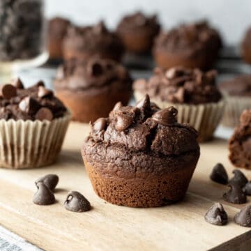 close up of vegan chocolate muffin with other muffins in background.