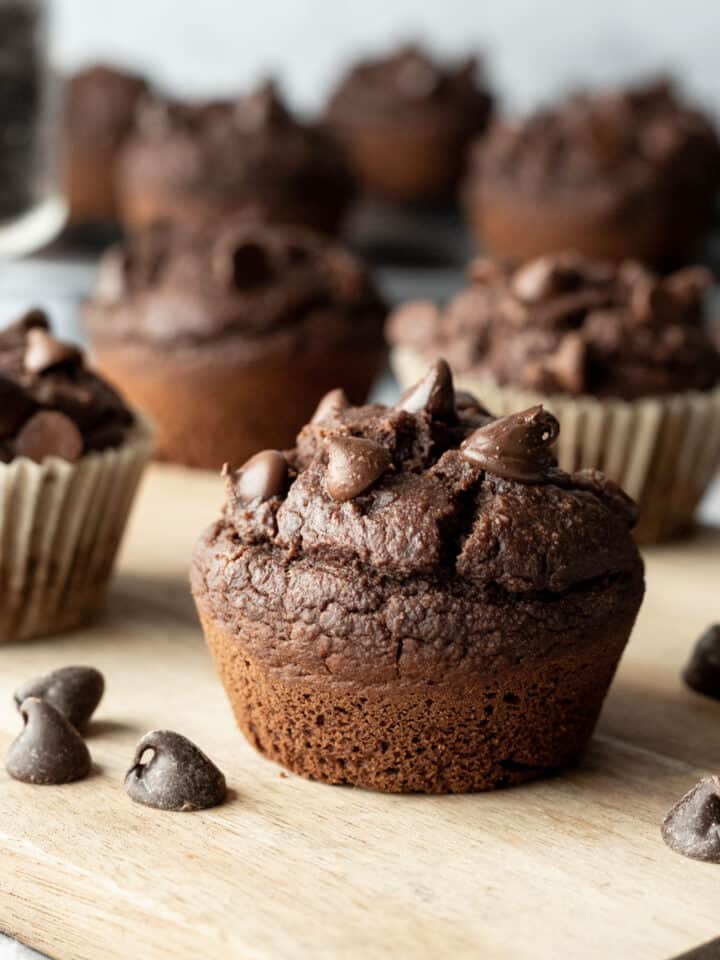 close up of vegan chocolate muffin with other muffins in background.