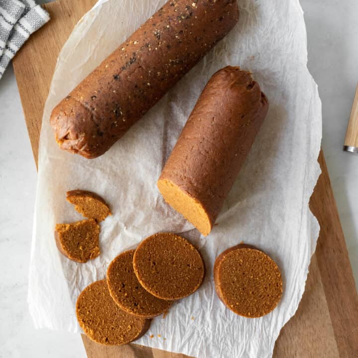 two pieces of seitan vegan chorizo on a wood board.