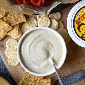 white ramekin filled with creamy homemade bitchin sauce surrounded by chips and veggies.