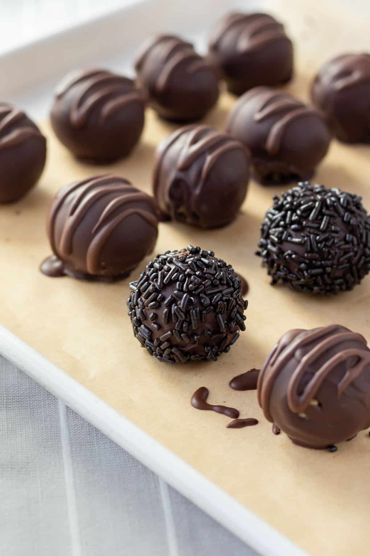balls of vegan cookie dough coated in chocolate and decorated with sprinkles.