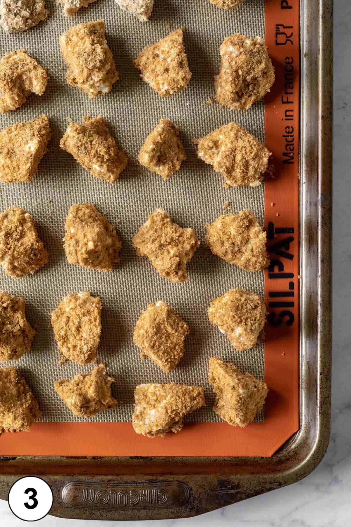 coated tofu nuggets on a silicone mat-lined baking tray ready for the oven.