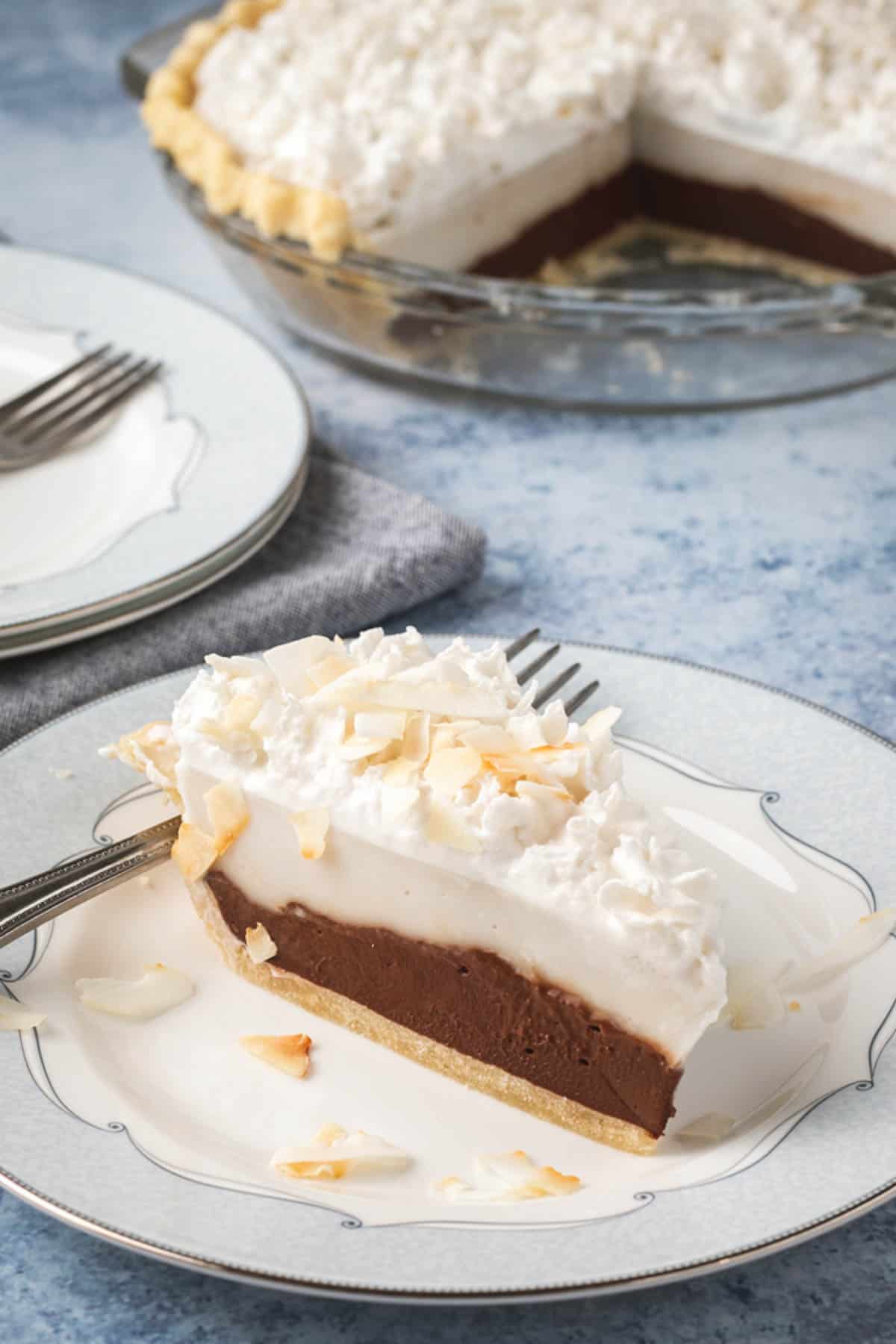 a slice of haupia pie on a plate showing the chocolate layer underneath a coconut layer.