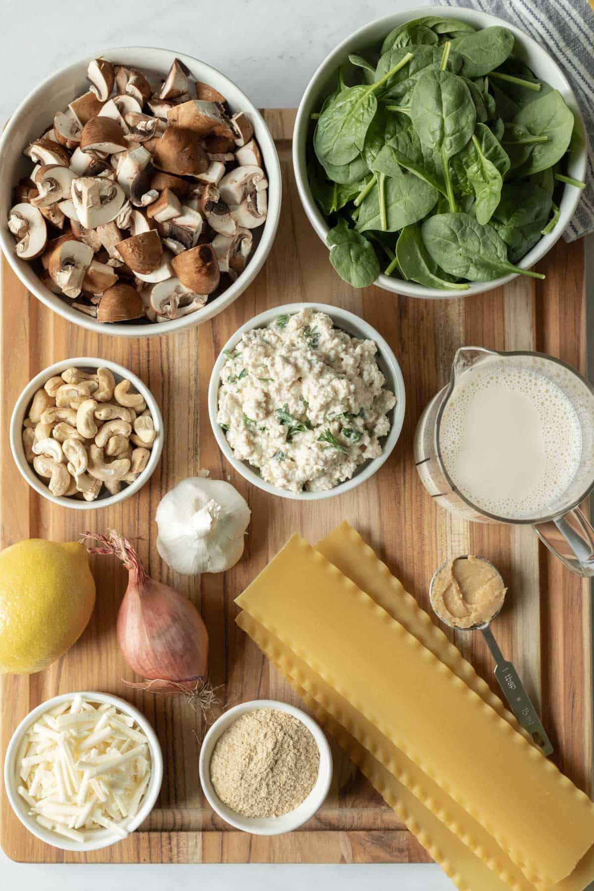 ingredients needed for white lasagna laid out on a large cutting board.