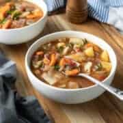 two white bowls filled with colorful vegetable soup.