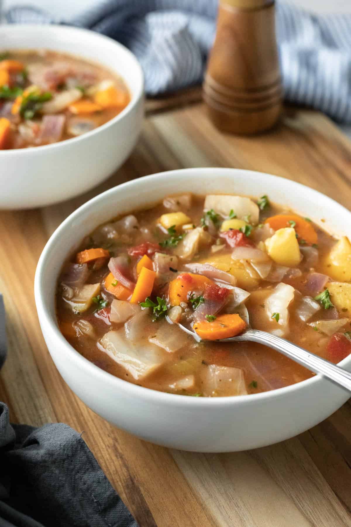 Colorful Instant Pot vegetable soup in a white bowl resting on a wooden serving board.