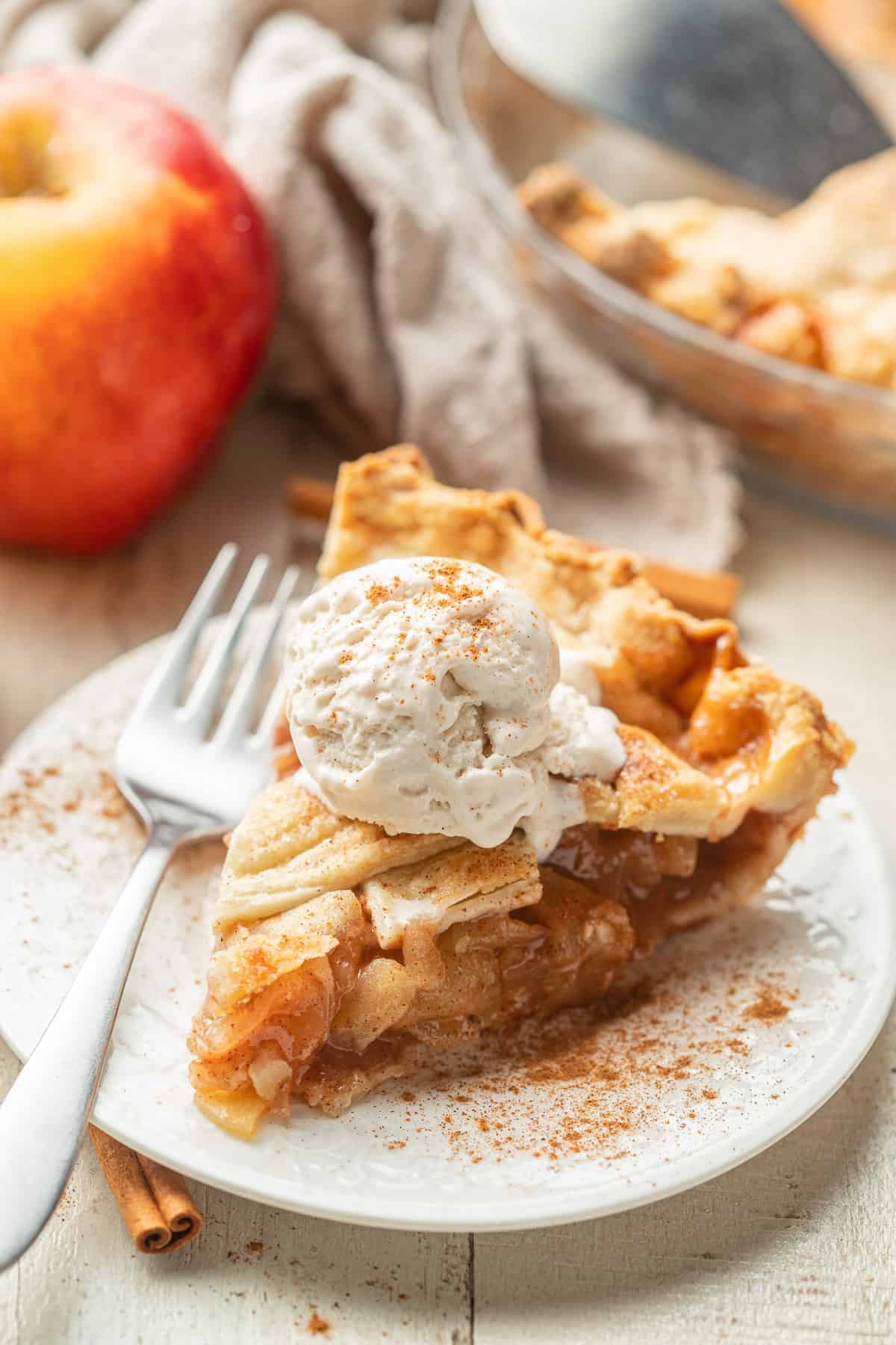 apple pie with a lattice top and scoop of ice cream on a small white plate.