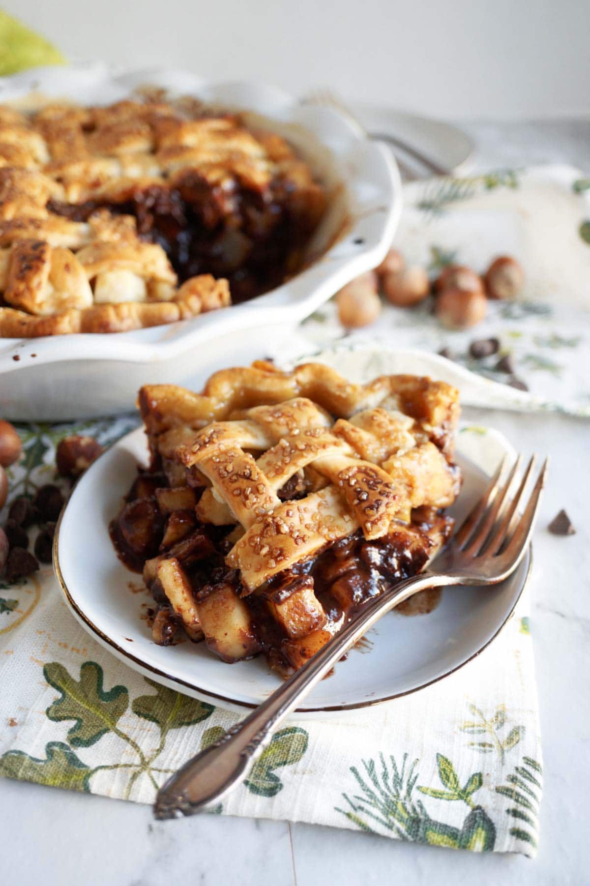 a slice of vegan pear pie on a small plate in a cozy tabletop setting.