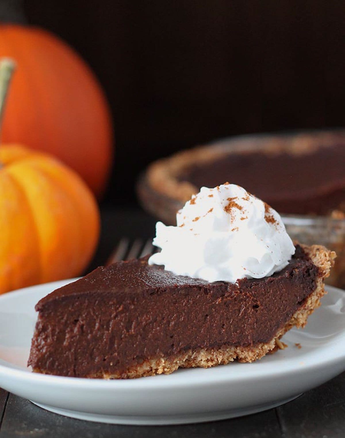 a slice of creamy-looking chocolate pumpkin pie with a dollop of dairy-free whipped topping.
