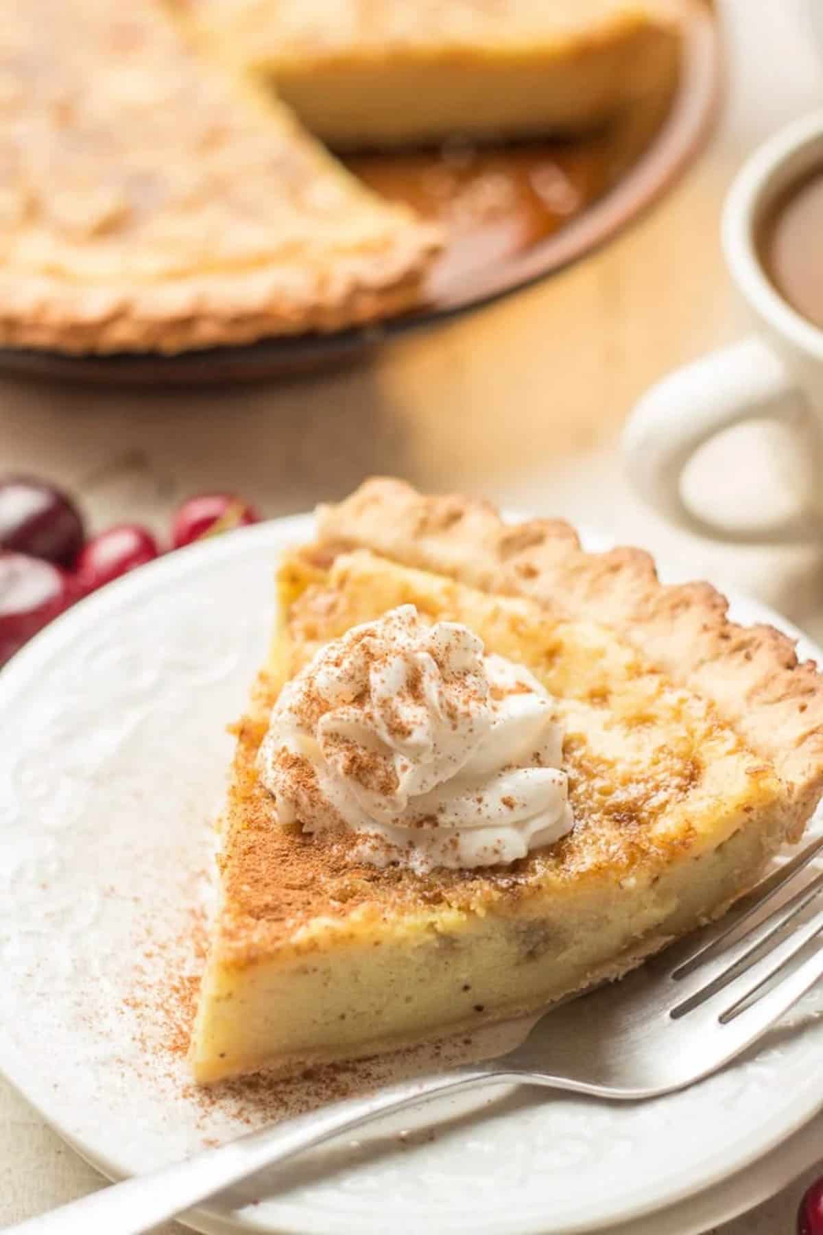 a slice of eggless custard pie on a small white plate next to a fork.