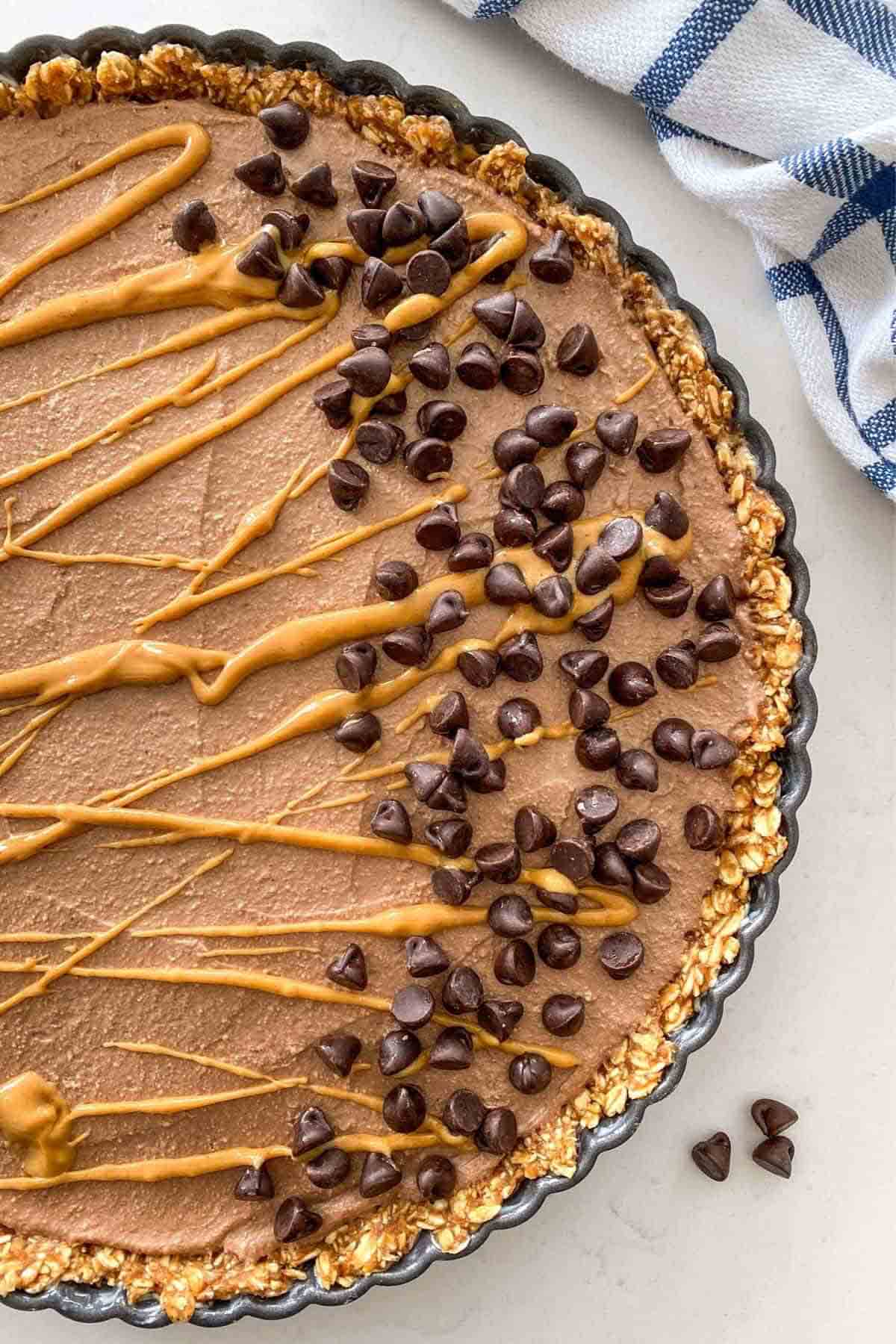 healthy peanut butter pie drizzled with nut butter and sprinkled with chocolate chips.
