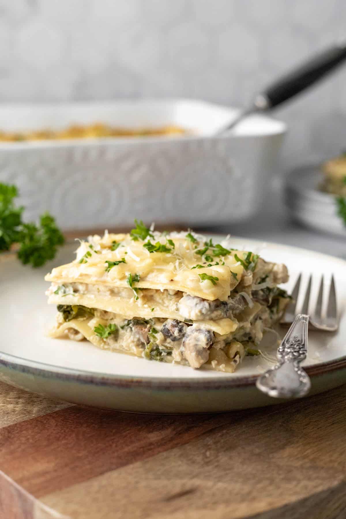 a square serving of vegan white lasagna on a small plate with a fork.