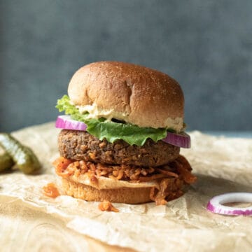 Air fryer vegan burger on a bun with kimchi, lettuce, onion, and mustard.