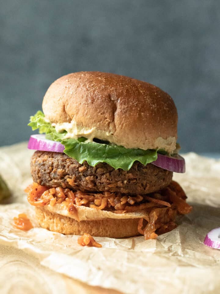 Air fryer vegan burger on a bun with kimchi, lettuce, onion, and mustard.