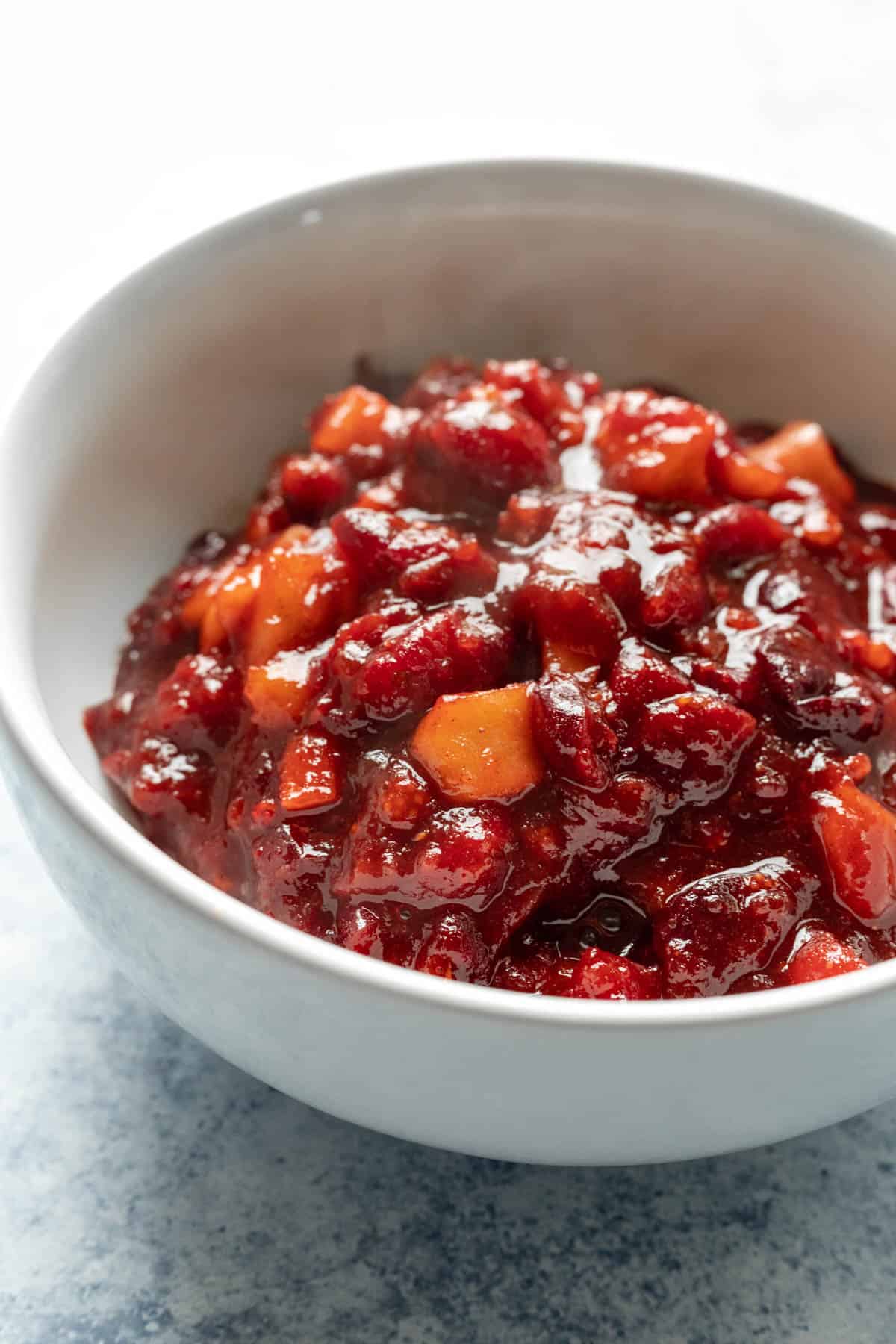chunky fruit compote in a white bowl on a blue countertop.