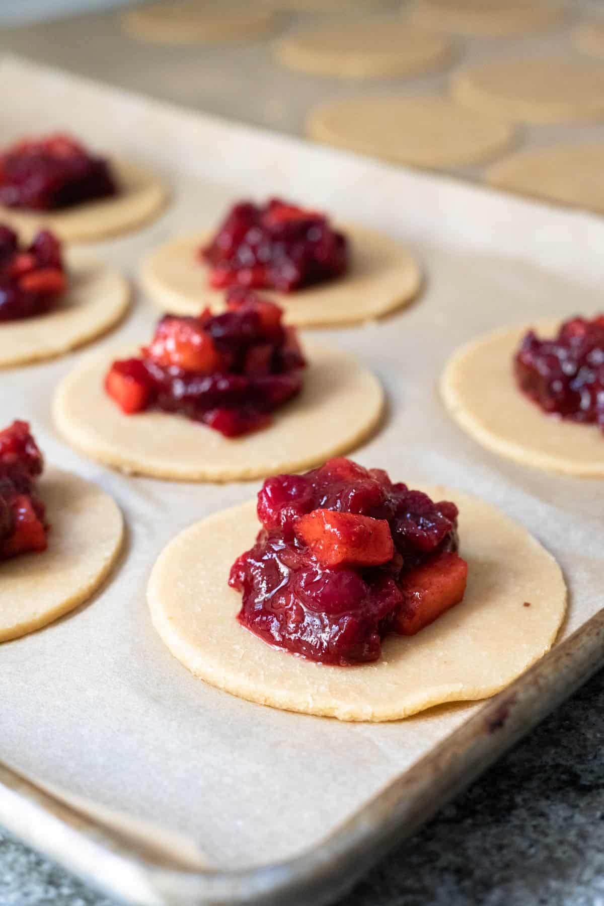dollops of cranberry compote on small rounds of pie dough for hand pies.