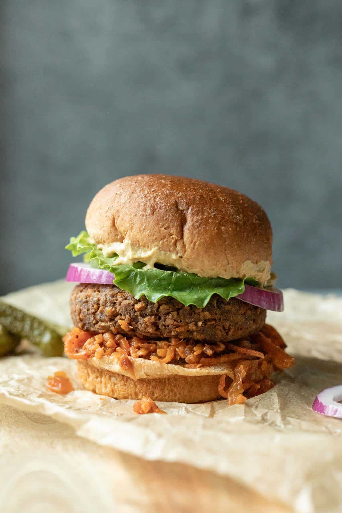 A loaded veggie burger on a bun against a blue background.