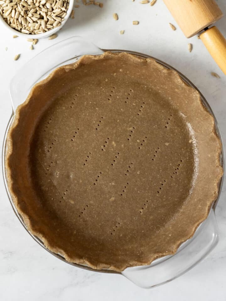 overhead view of unbaked sunflower seed pie crust in glass pie plate.