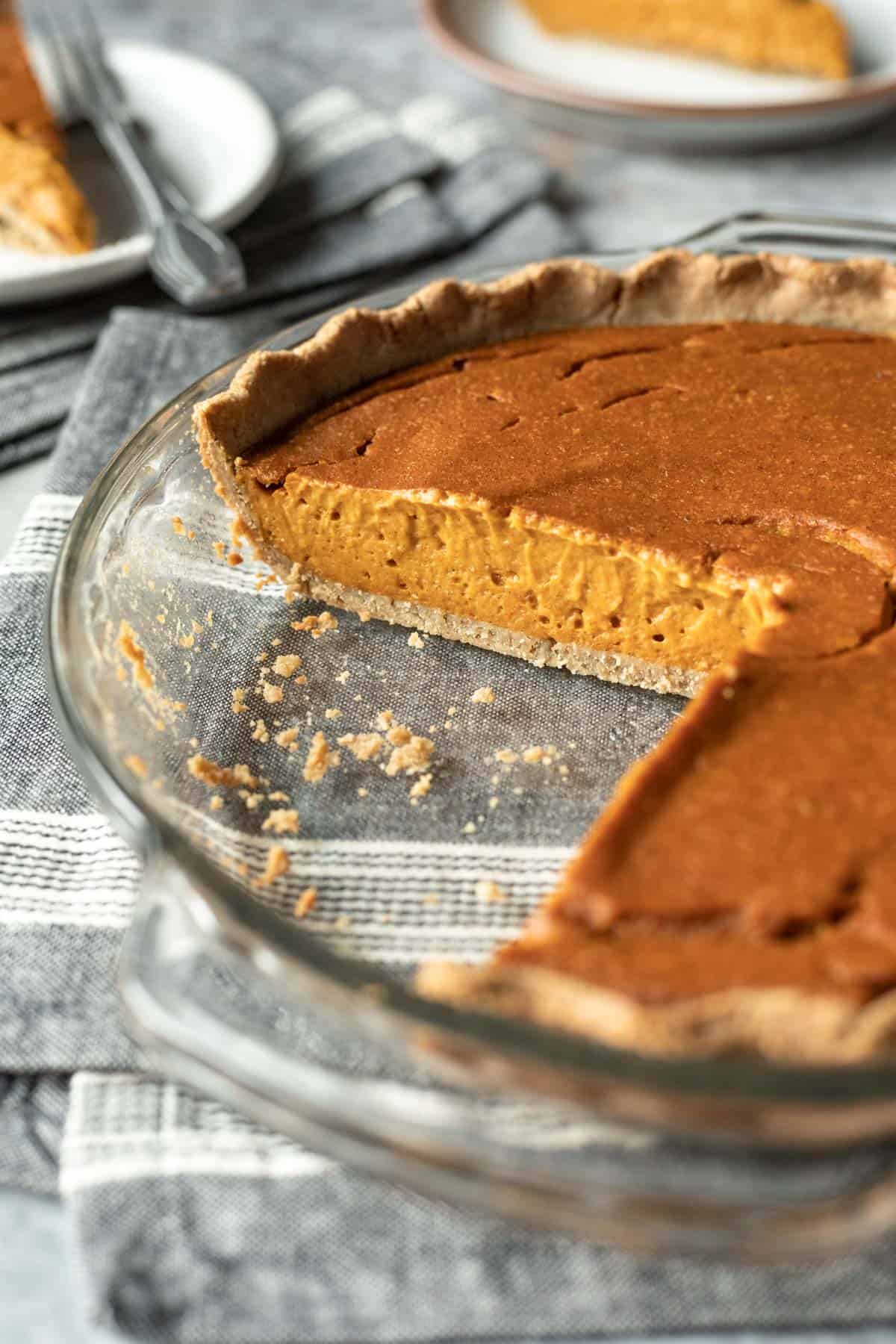 vegan pumpkin pie in pie plate with slices removed to show texture of the nut-free pie crust.