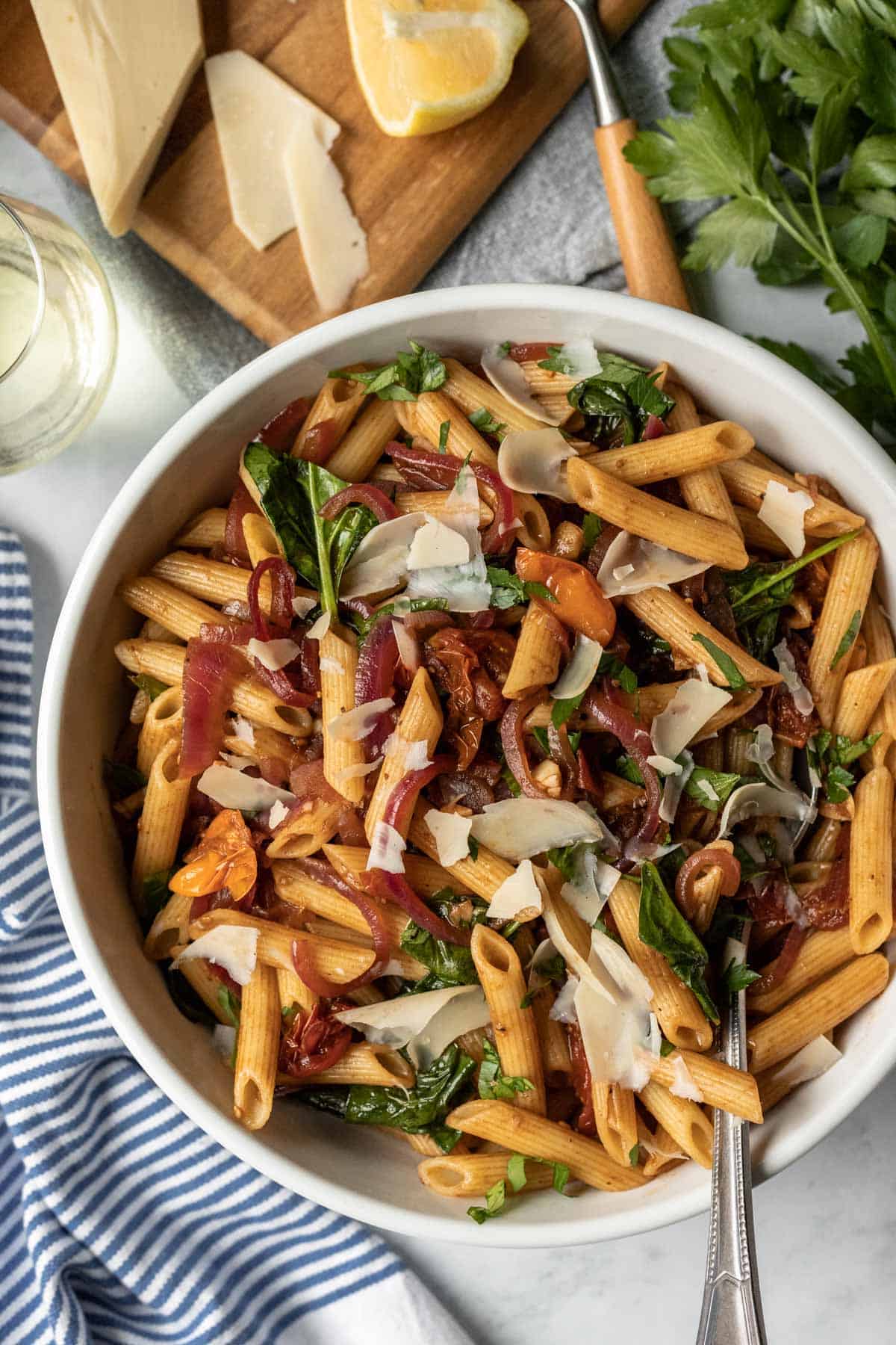 large white serving bowl filled with pasta fresca topped with vegan parmesan cheese.