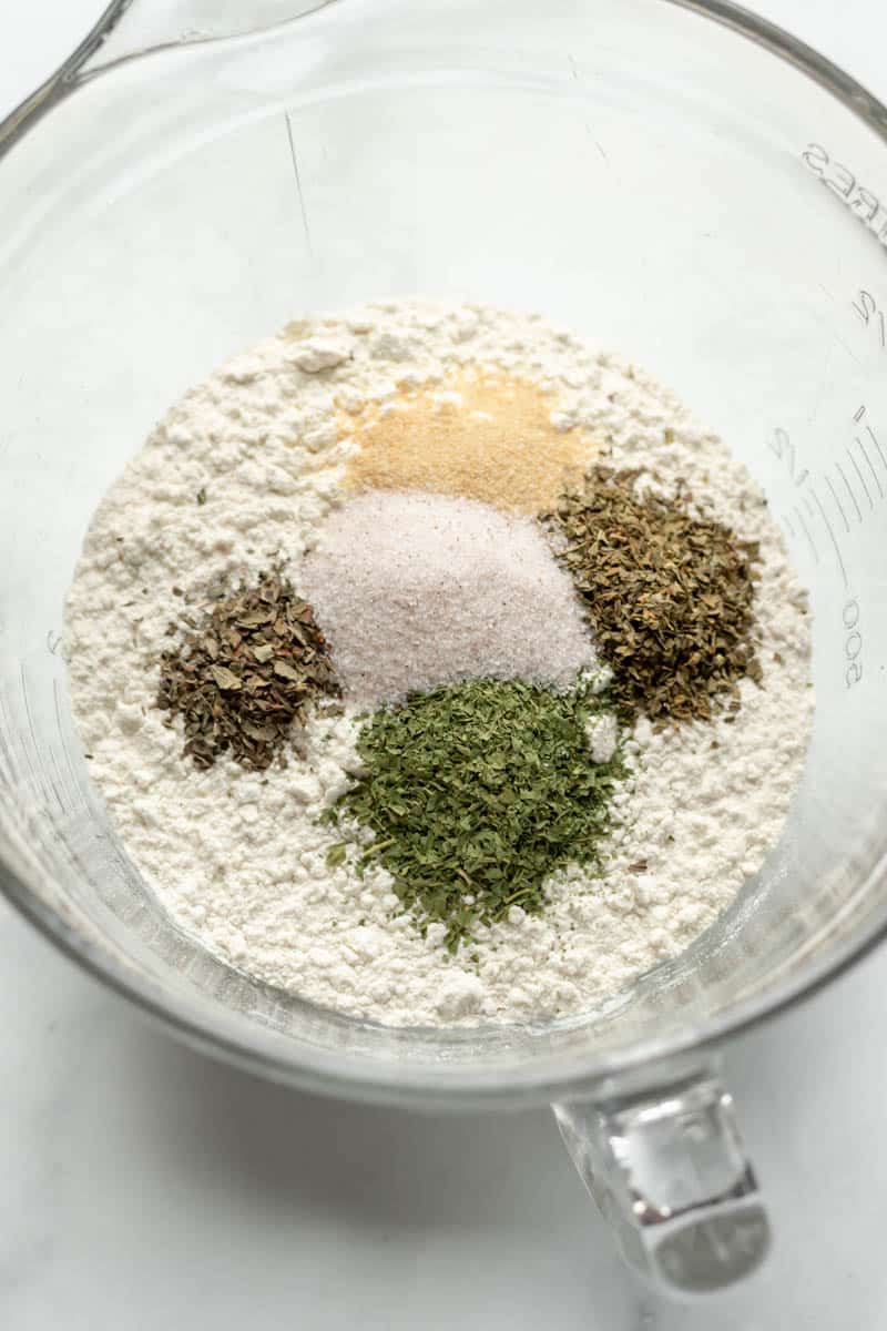 flour, salt, and dried herbs in a glass mixing bowl.