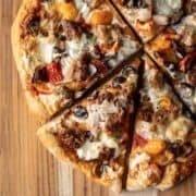 vegan pizza made with an herb crust on a wood cutting board.