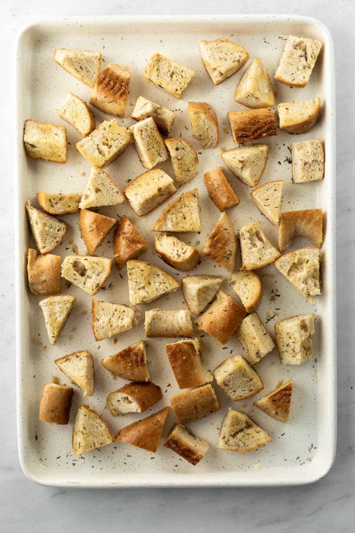 stale bread on a baking sheet drizzled with olive oil and seasoned with herbs and salt.
